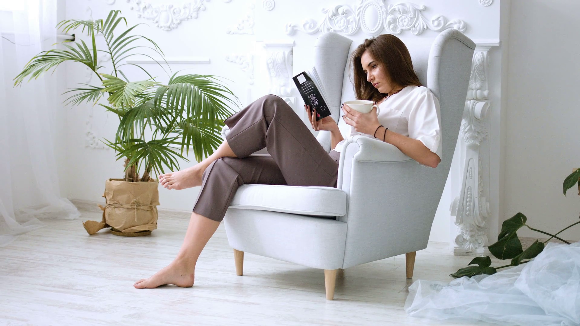 videoblocks-pretty-girl-drinking-coffee-or-tea-and-relaxing-in-chair-reading-a-book_rw5ucyr-b_thumbnail-full01